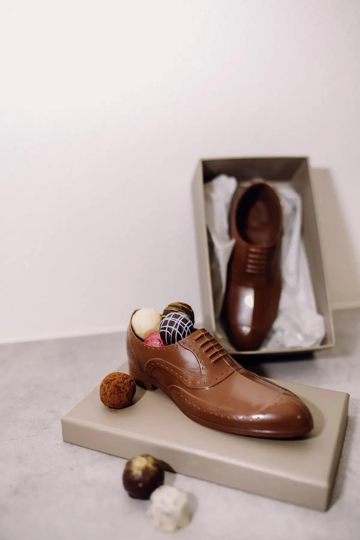 Herrenschuh aus Schokolade, gefüllt mit Pralinen, in einer Schuhschachtel