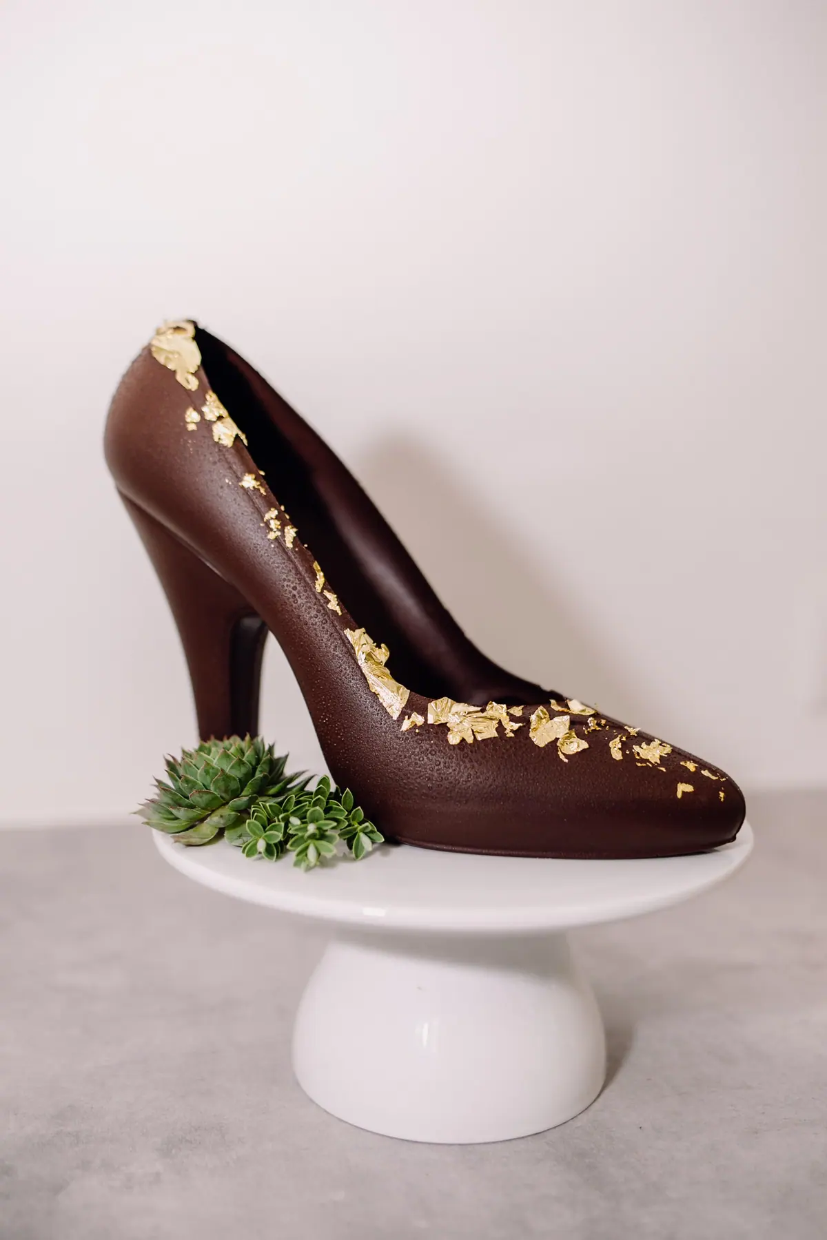 High Heel aus Zartbitterschokolade mit Blattgold auf einer weißen Etagere