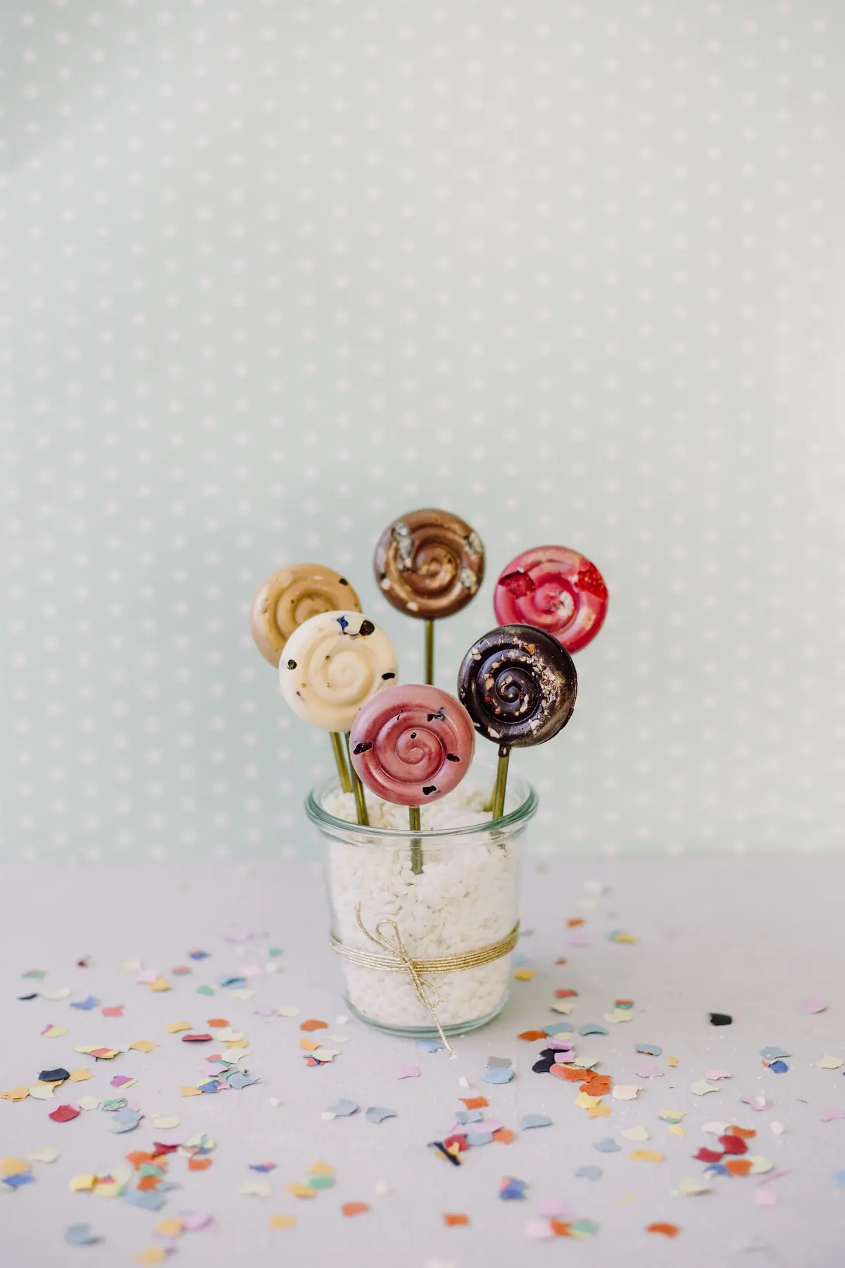 Strauß aus Schoko-Lollies in einem Glas, rundherum buntes Konfetti