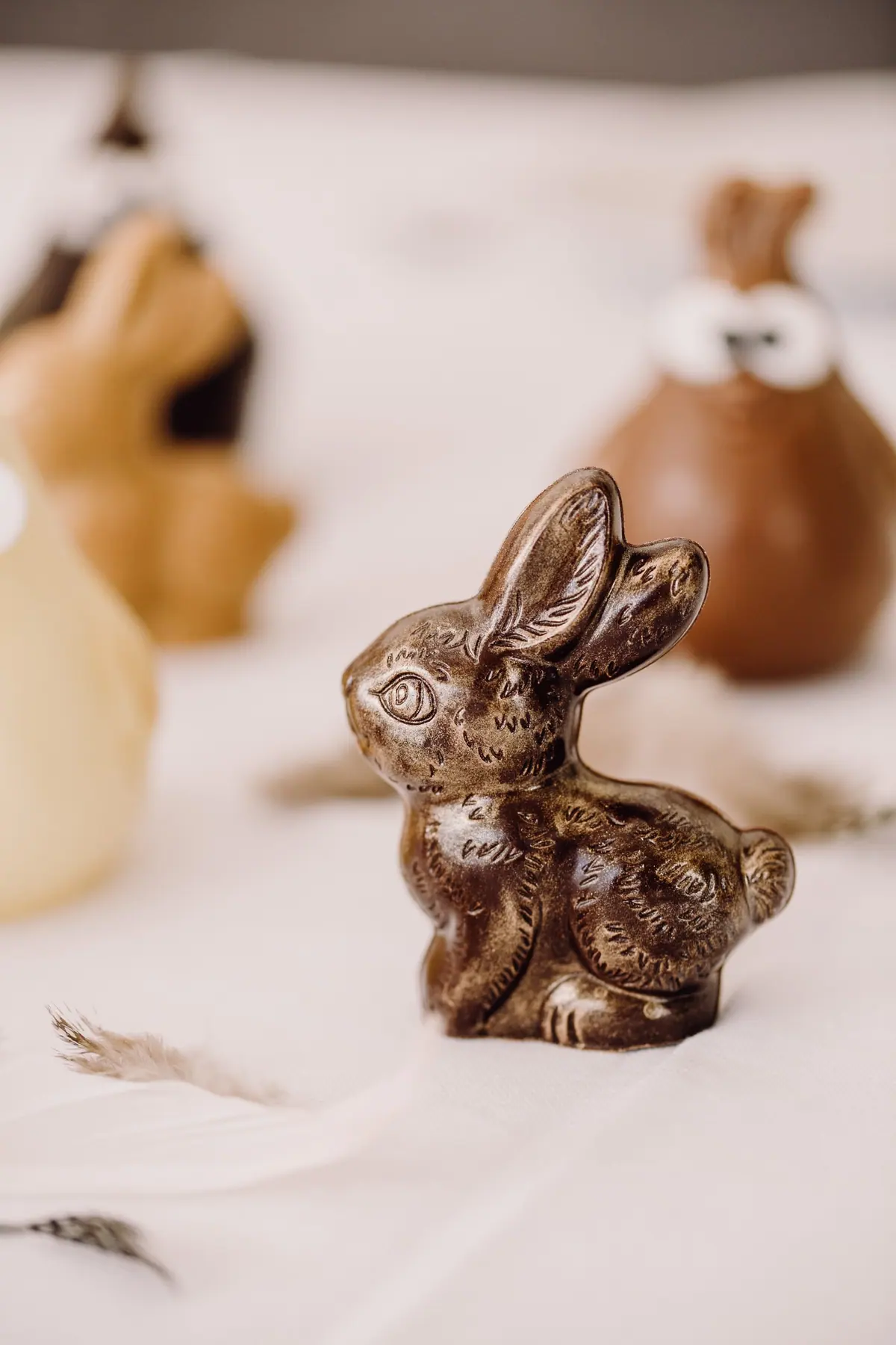 Kleiner Osterhase aus Zartbitterschokolade vor weiteren Osterfiguren