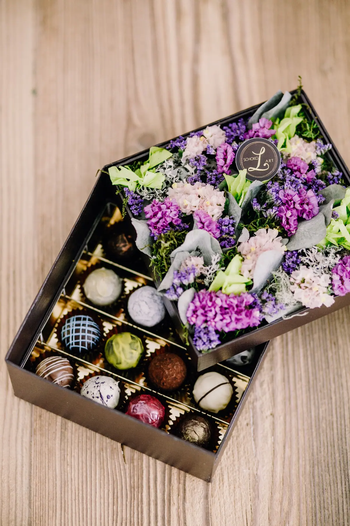 Schatulle mit Pralinen und einem Strauß aus Flieder und Wiesenblumen