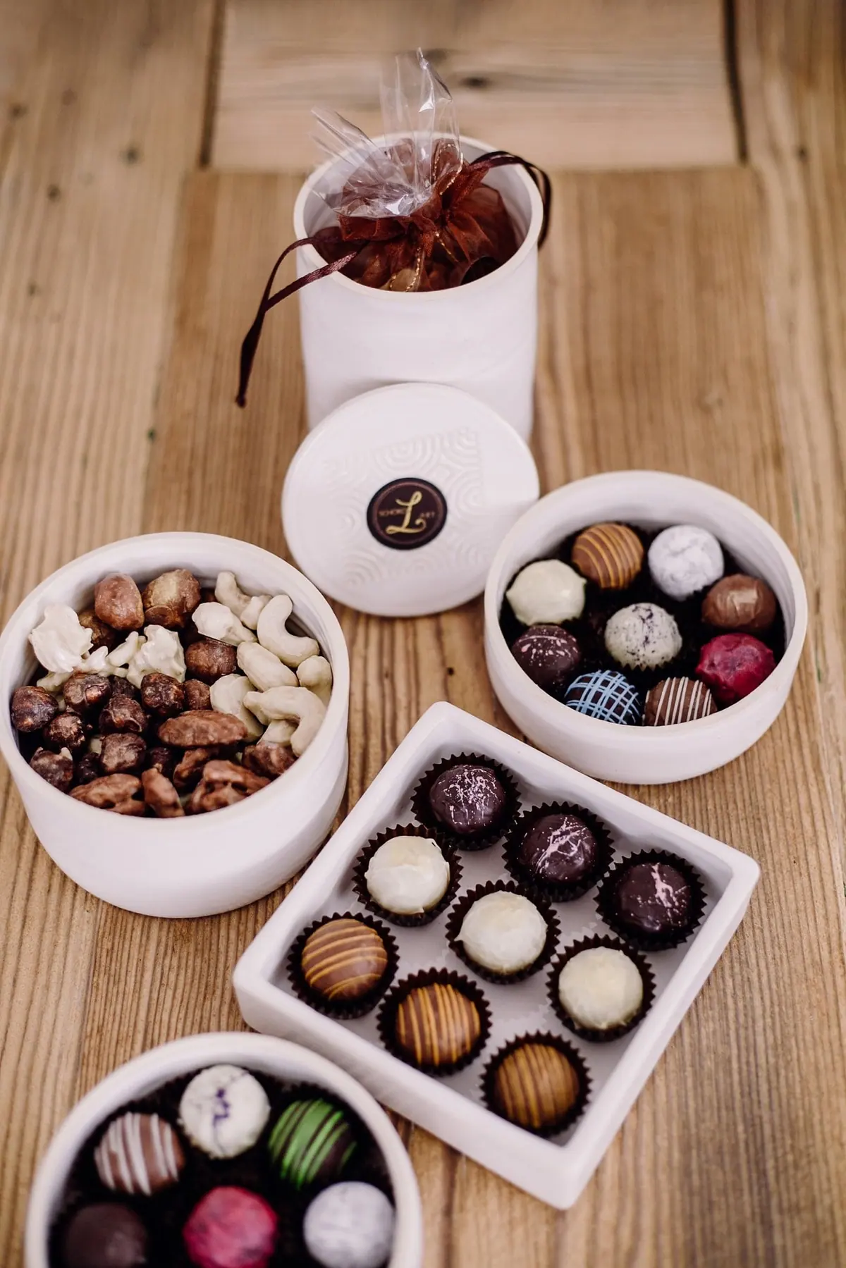 Gedeckter Tisch mit Keramikschalen voller Pralinen, Nüssen und Trüffeln von oben