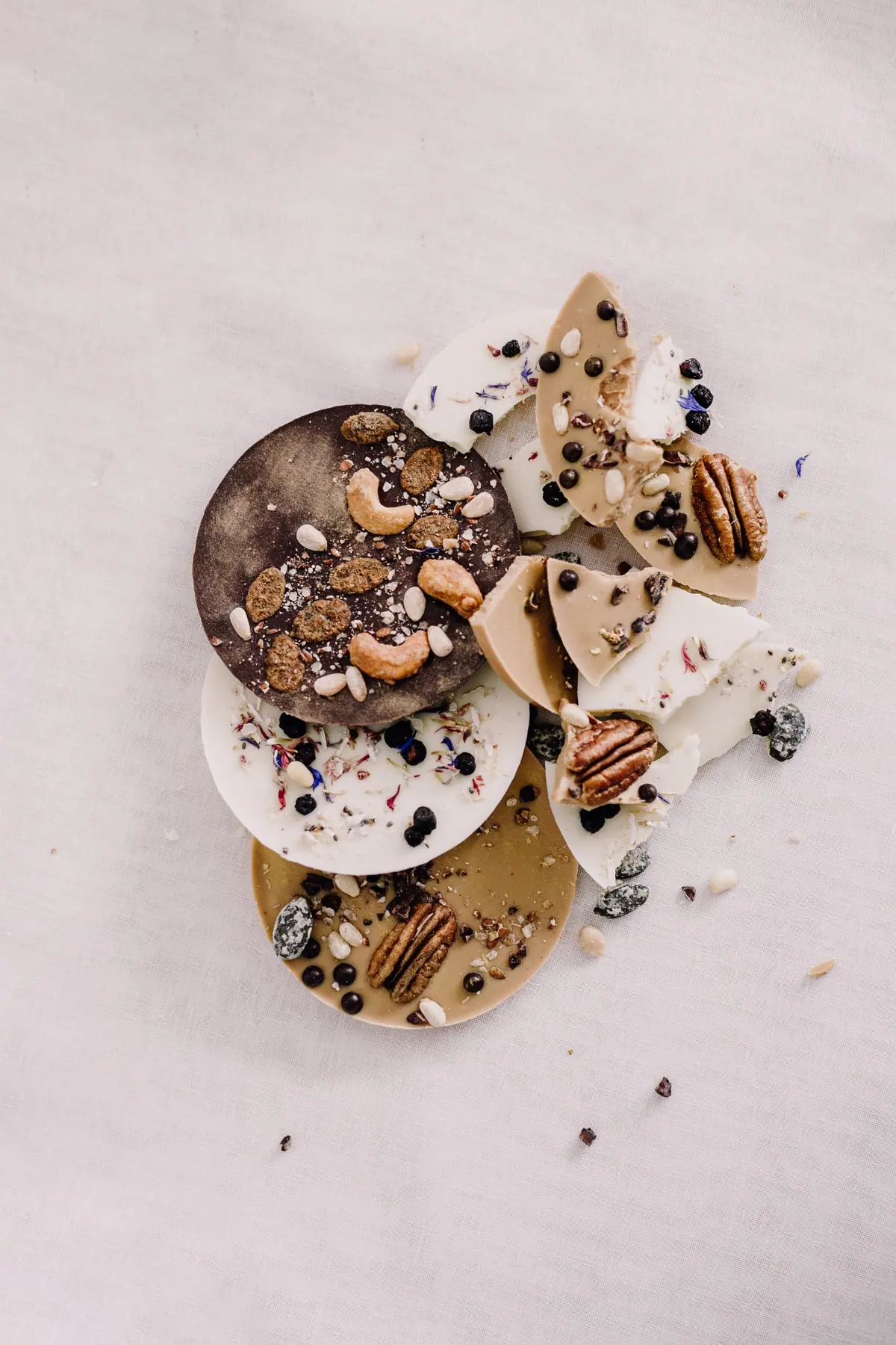 Schokotaler mit Cashews, Pekannüssen und Blüten, kreisförmig gelegt