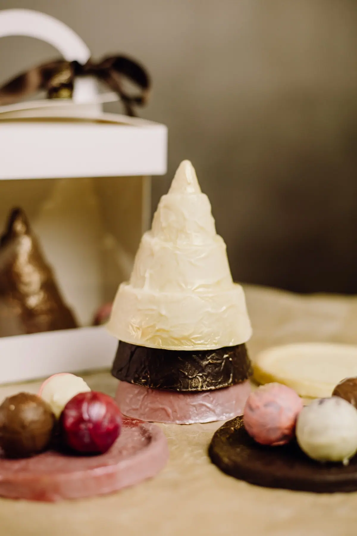 Weißer Schoko-Christbaum mit Goldverzierung zwischen Trüffeln