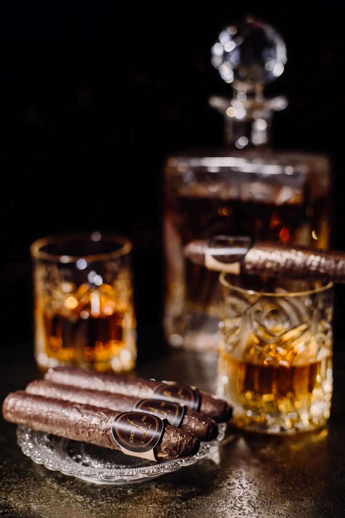 Mehrere Schokozigarren auf einem Kristallteller vor Whiskyglas und Karaffe